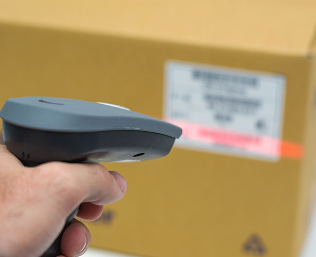 Barcode Scanner scanning a brown box and white label with lot tracking information