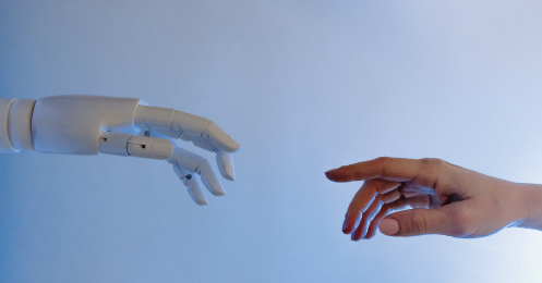 Robot hand and human hand interacting to show how AI Tools for businesses are beneficial